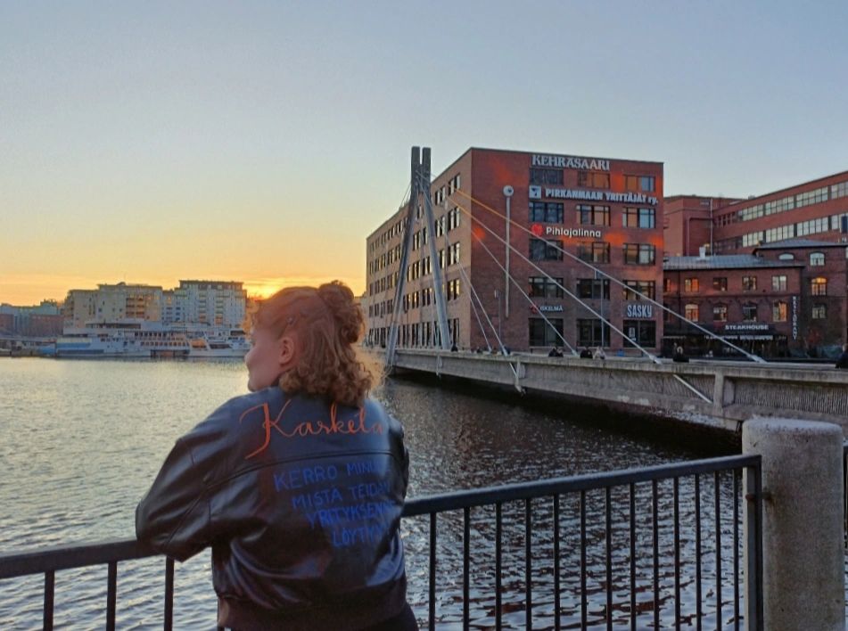 Kasketan yrittäjä ja toimitusjohtaja nojaamassa Tammerkosken kaiteeseen, nahkatakin selässä lukee "Kasketa" ja "kerro minulle mistä teidän yrityksenne löytyy".